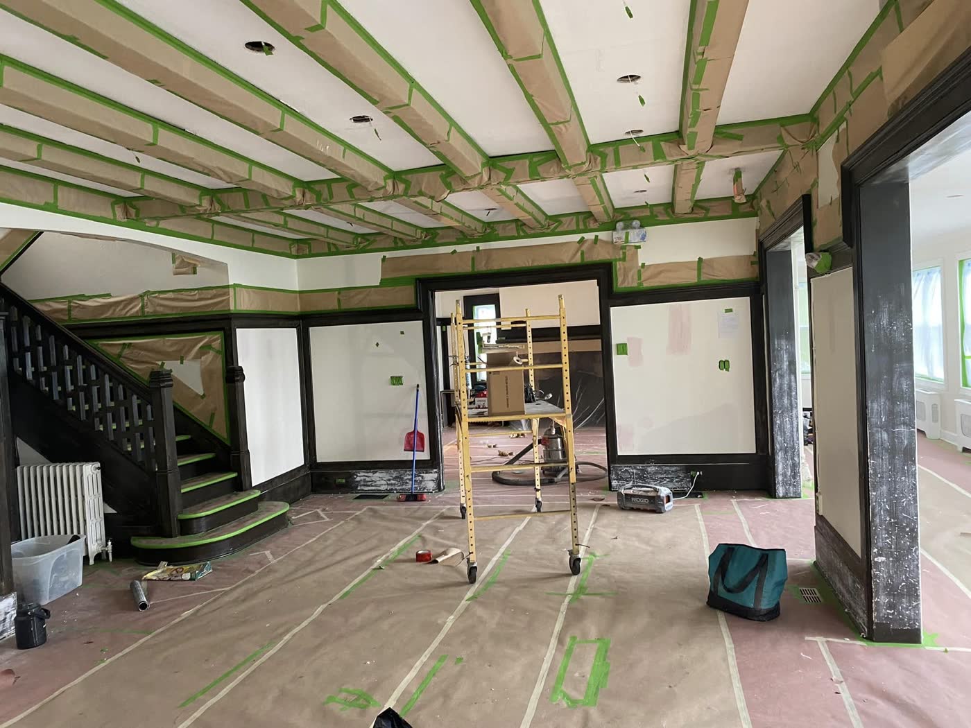 Plafond à poutres masqué au ruban vert, plancher couvert de papier