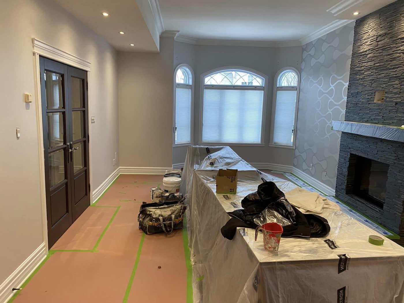 Séjour en travaux, îlot et meubles couverts de plastique